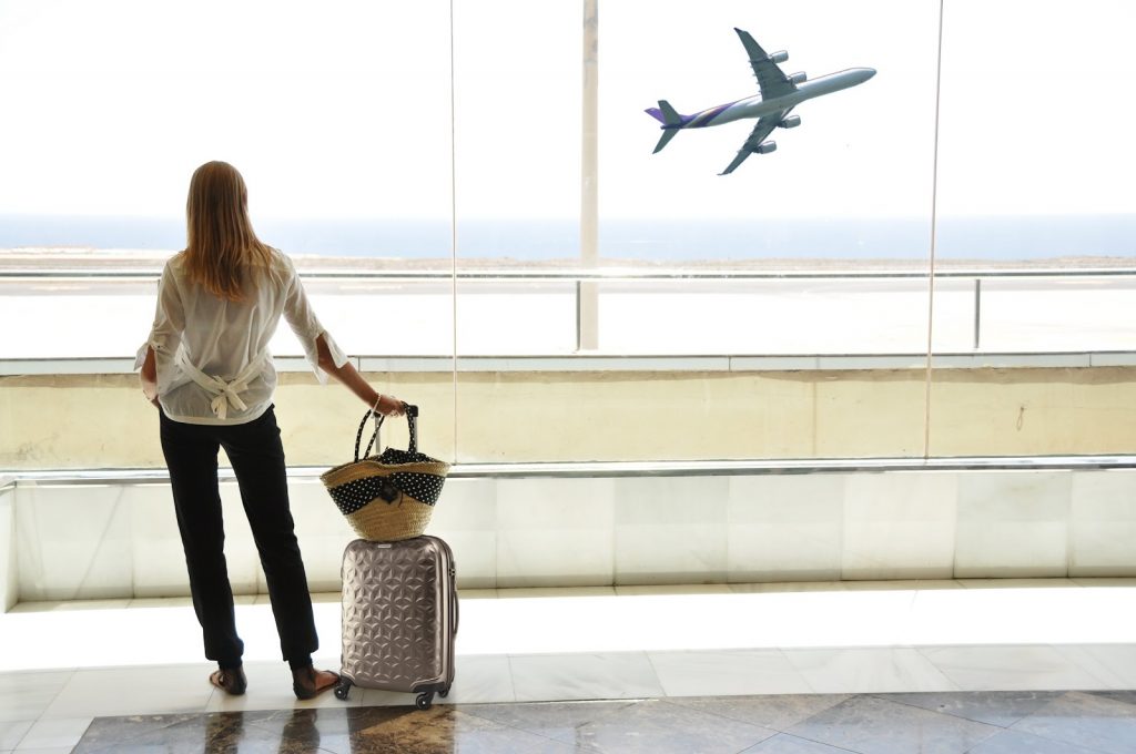 Mulher olhando o avião pelo vidro do aeroporto